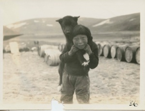 Image of Inuit boy with dog on shoulders